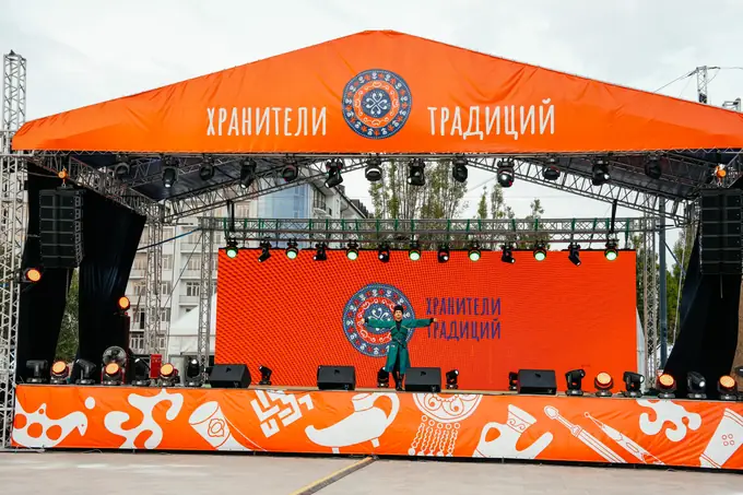 Оранжевая главная сцена с надписью «Хранители традиций» и артистом